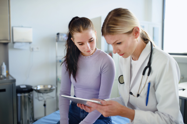 Young woman doctor explaining diagnosis to teenage girl in her ambulance office.