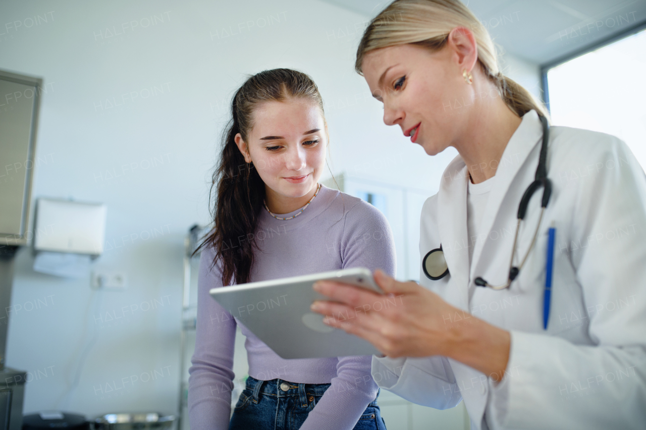 Young woman doctor explaining diagnosis to teenage girl in her ambulance office.