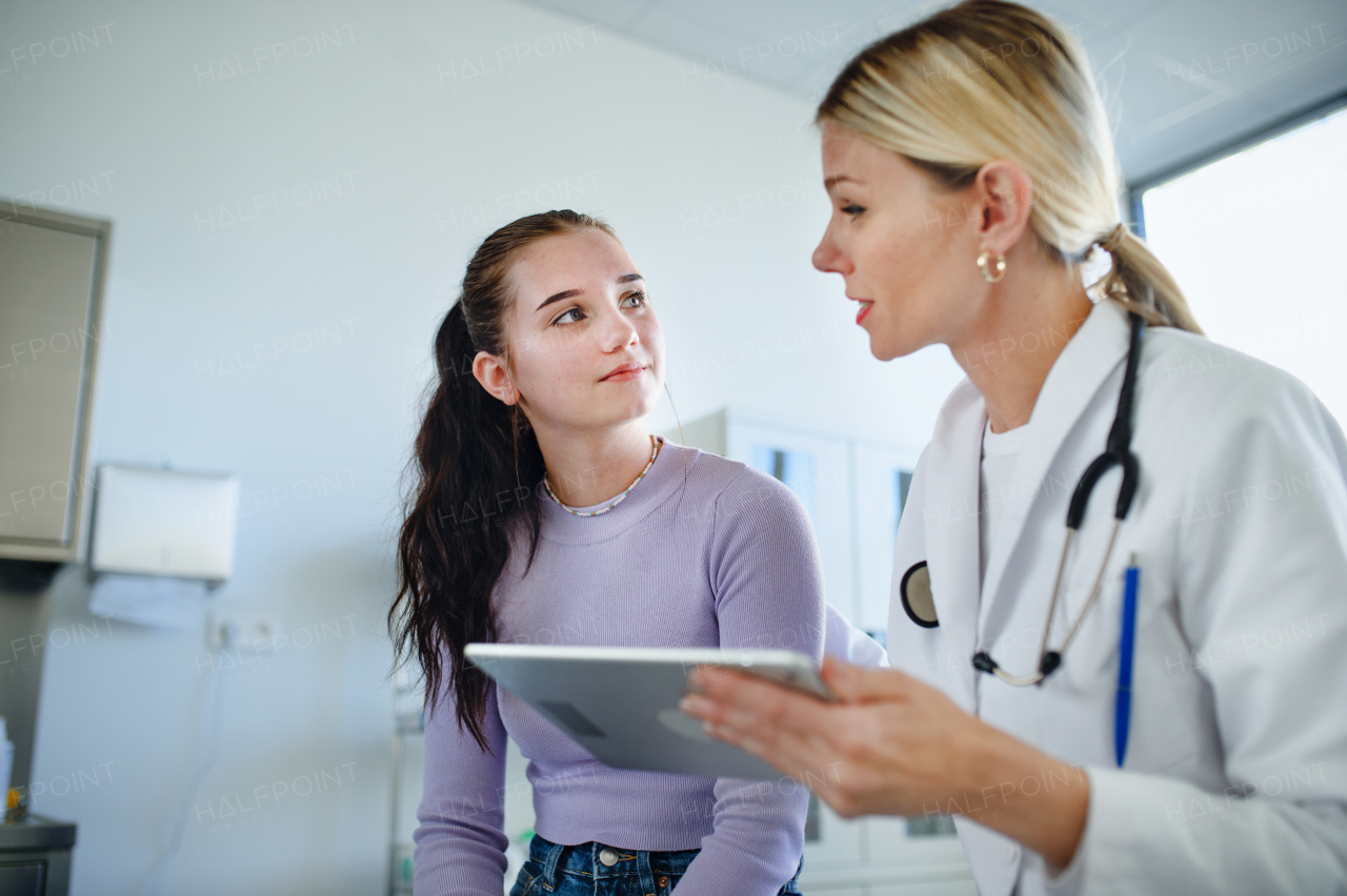 Young woman doctor explaining diagnosis to teenage girl in her ambulance office.