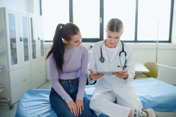 Young woman doctor explaining diagnosis to teenage girl in her ambulance office.