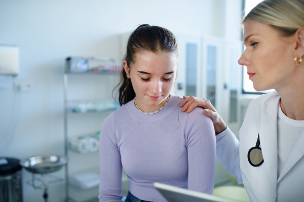 Close-up of doctor consoling unhappy teenage girl in the ambulance office.