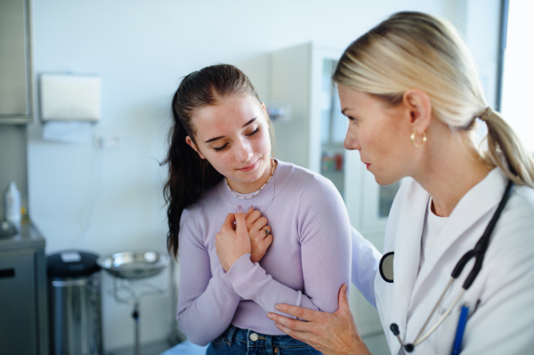 Young woman doctor explaining diagnosis to teenage girl in her ambulance office.