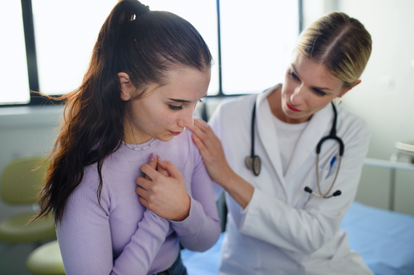 Close-up of doctor consoling unhappy teenage girl in the ambulance office.