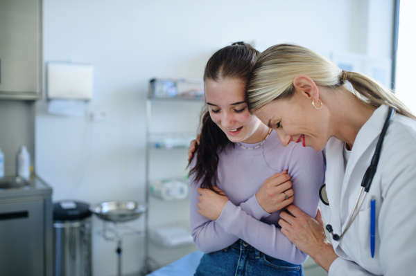 Young woman doctor smiling with teenage girl in the ambulance.