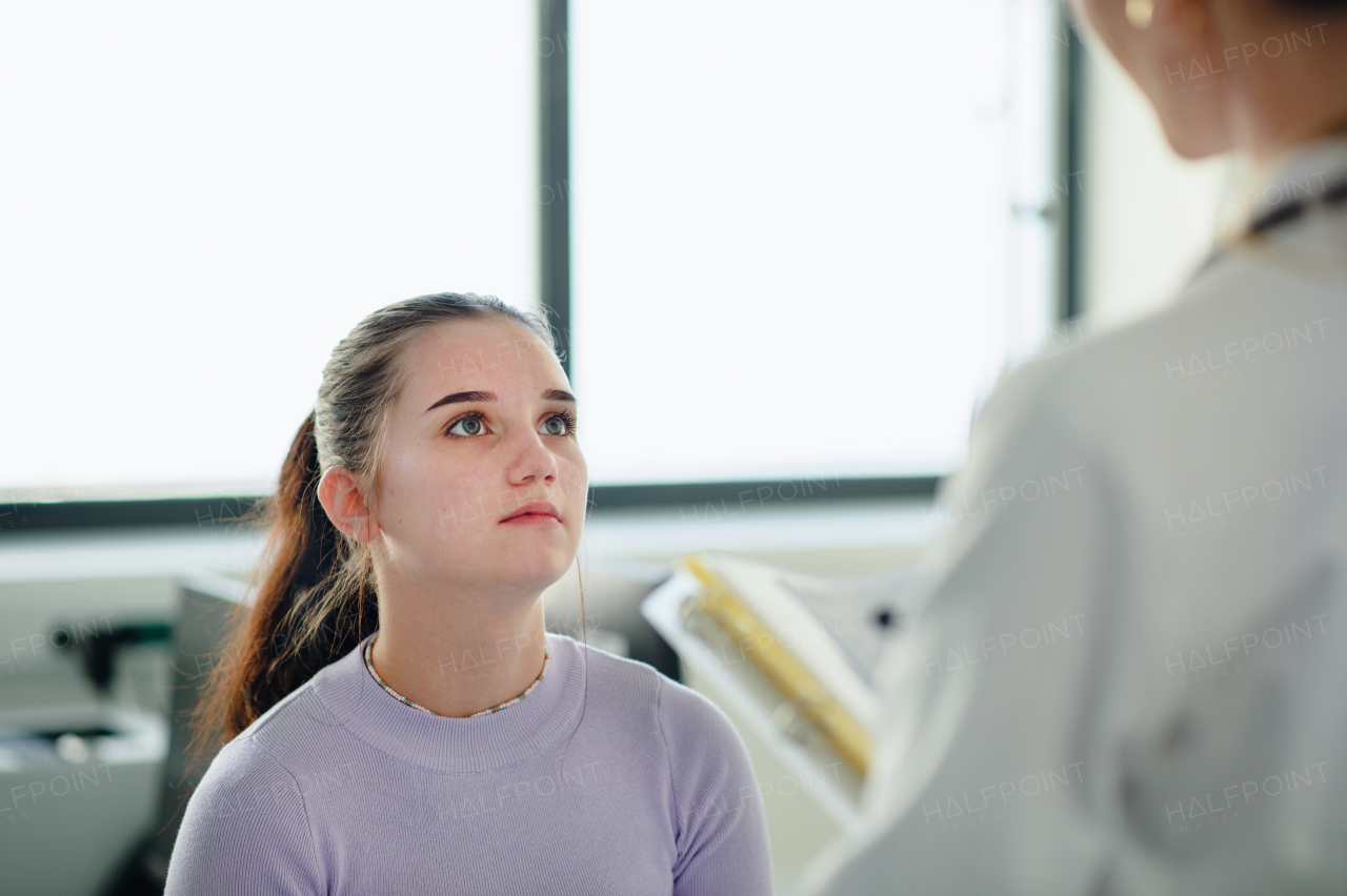 Young woman doctor explaining diagnosis to teenage girl in her ambulance office.