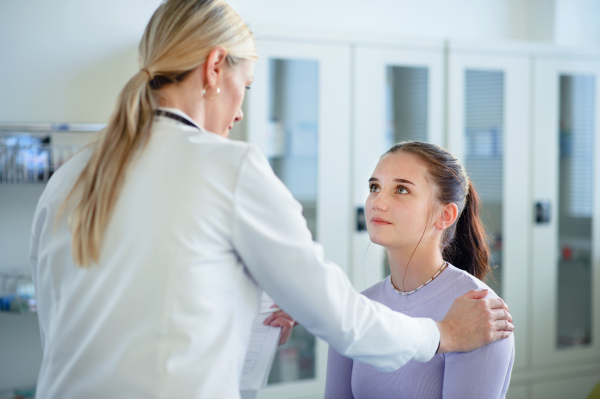 Close-up of doctor consoling unhappy teenage girl in the ambulance office.