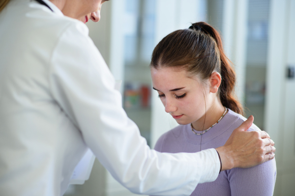 Close-up of doctor consoling unhappy teenage girl in the ambulance office.