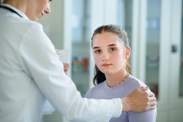 Close-up of doctor consoling unhappy teenage girl in the ambulance office.