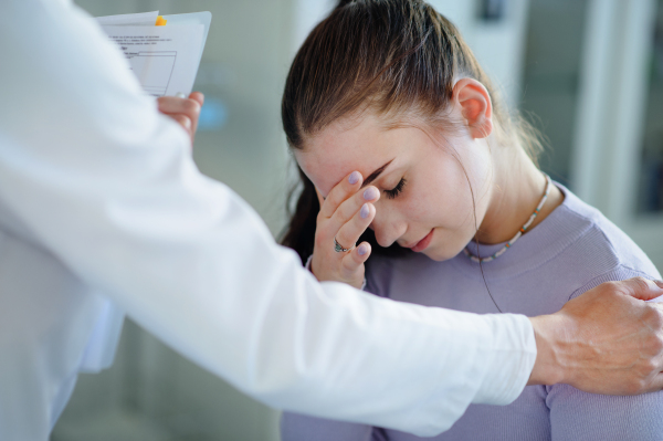 Close-up of doctor consoling unhappy teenage girl in the ambulance office.