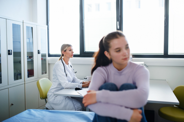 Unhappy teenage girl sitting in a doctor's office.