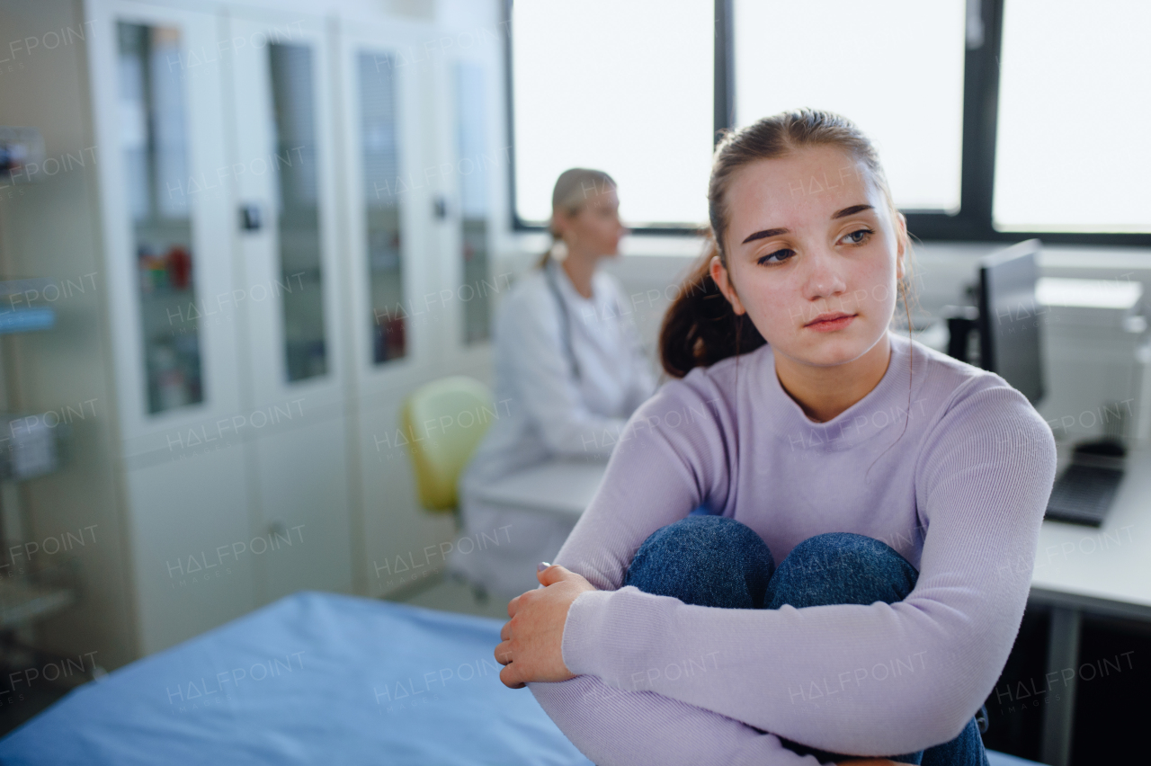 Unhappy teenage girl sitting in a doctor's office.