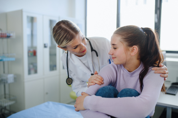 Close-up of doctor consoling teenage girl in the ambulance office.