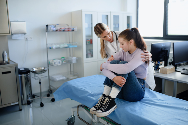 Young woman doctor talking with unhappy teenage girl in the ambulance.