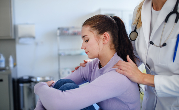 Close-up of doctor consoling unhappy teenage girl in the ambulance office.