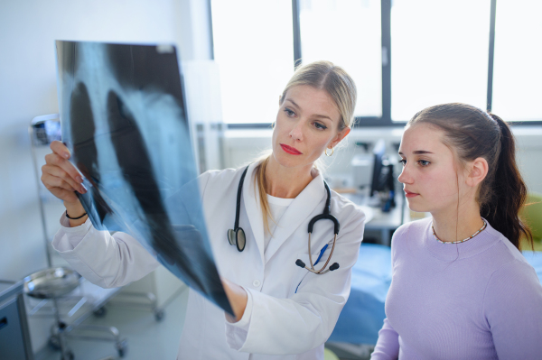 Young woman doctor showing x-ray image of lungs to the patient.