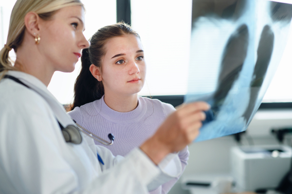 Young woman doctor showing x-ray image of lungs to the patient.