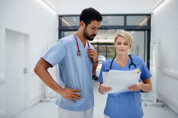 Pregnant doctor talking with her colleague at the hospital corridor.