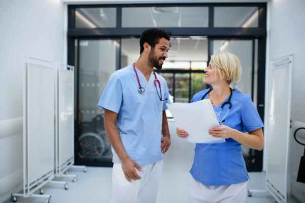 Pregnant doctor talking with her colleague at the hospital corridor.