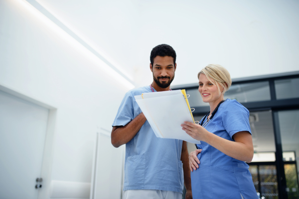 Pregnant doctor talking with her colleague at the hospital corridor.