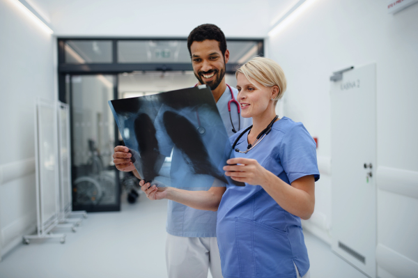 Pregnant doctor checking x-ray image with her colleague at the hospital corridor.