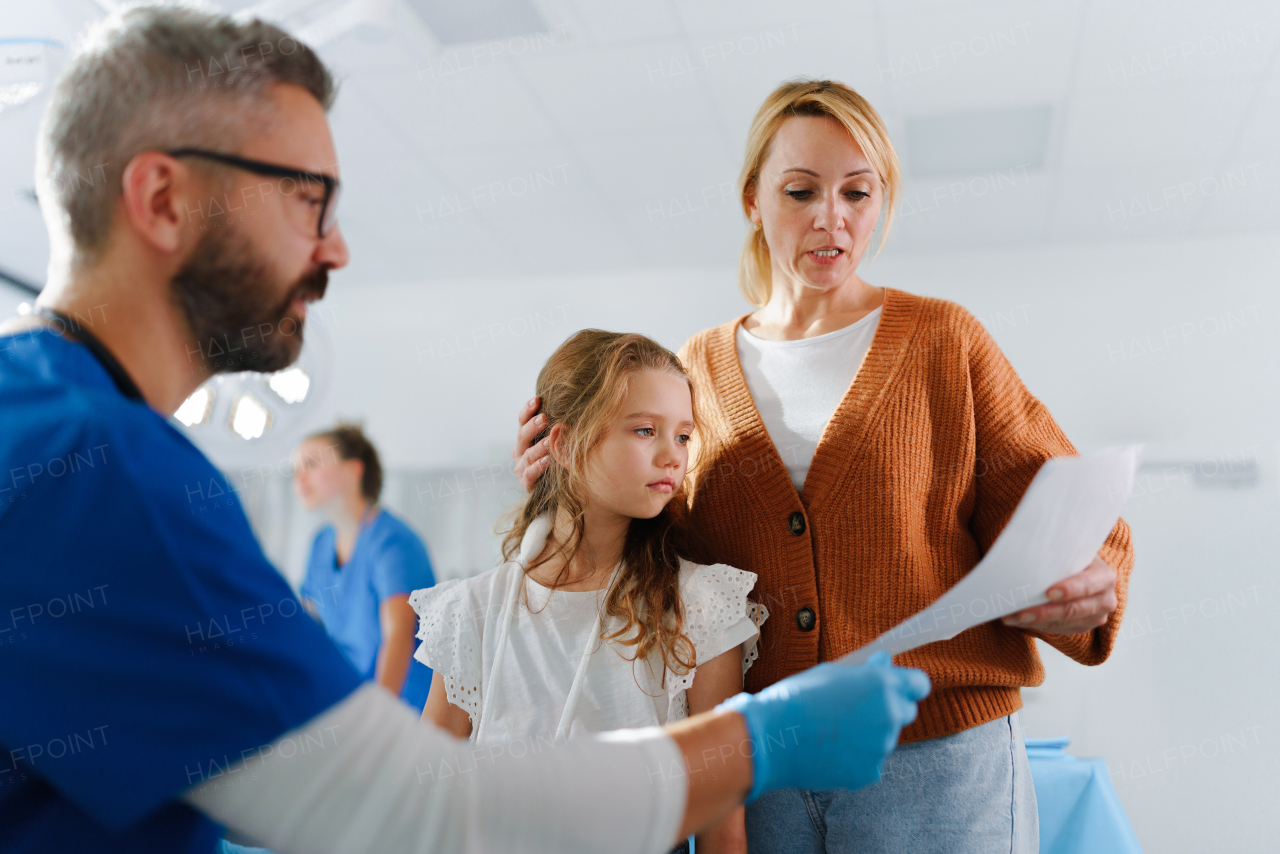 Doctor explaining something to mother of little girl with injured arm.