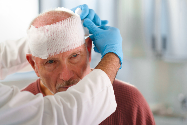 Close-up of doctor treating injured head of senior man.