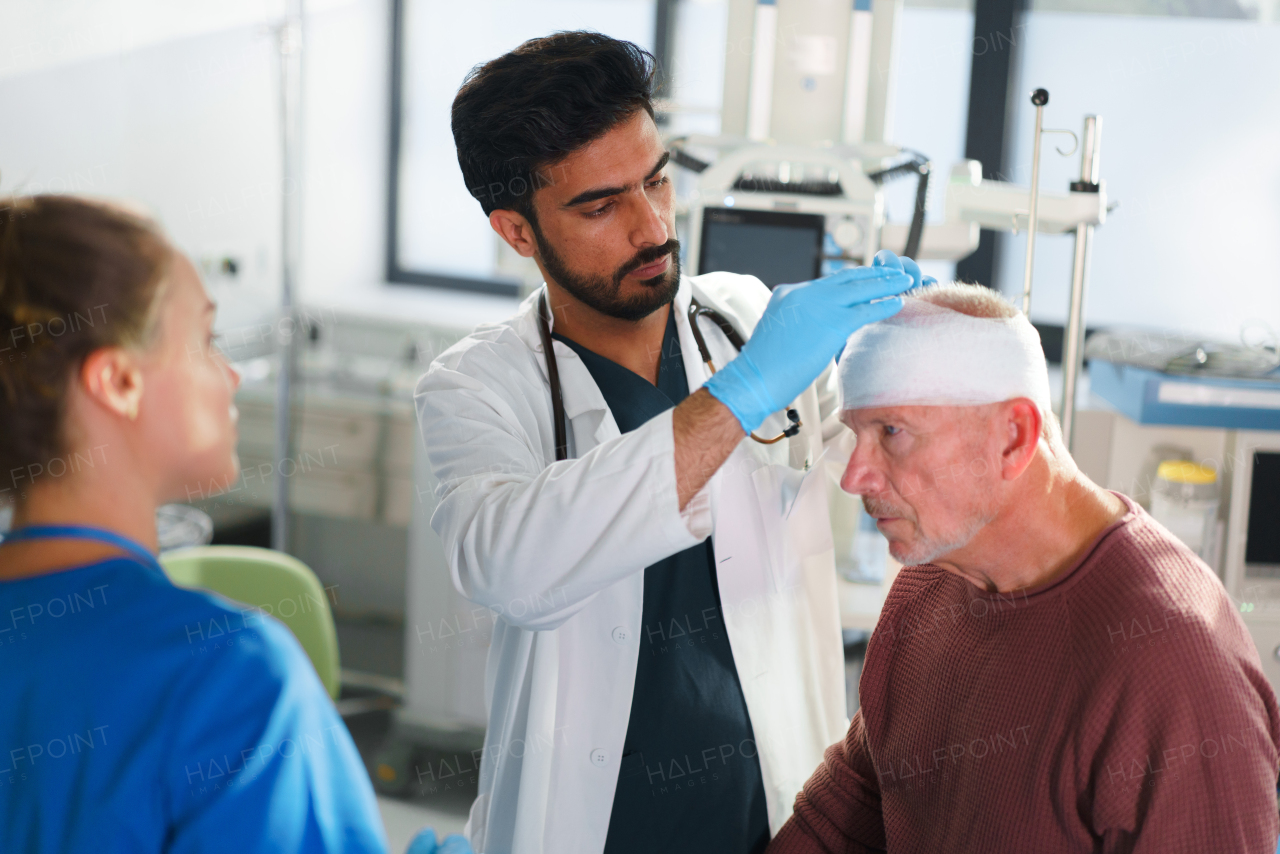 Close-up of doctor and nurse treating injured head of senior man.