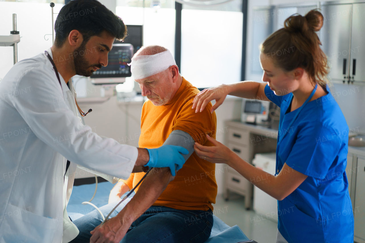 Close-up of doctor and nurse treating injured head of senior man.