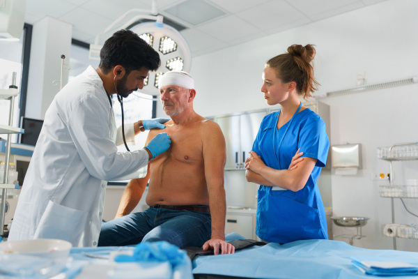 Young doctor and nurse treating of injured senior man.