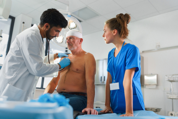 Young doctor and nurse treating of injured senior man.