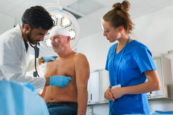 Close-up of doctor and nurse treating injured head of senior man.