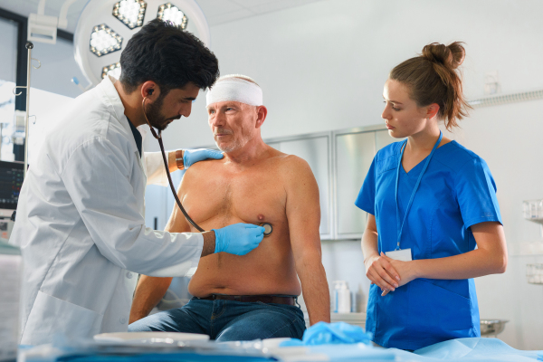 Young doctor and nurse treating of injured senior man.