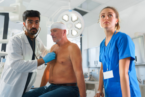 Young doctor and nurse treating of injured senior man.