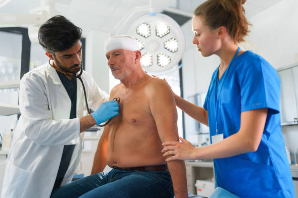 Young doctor and nurse treating of injured senior man.