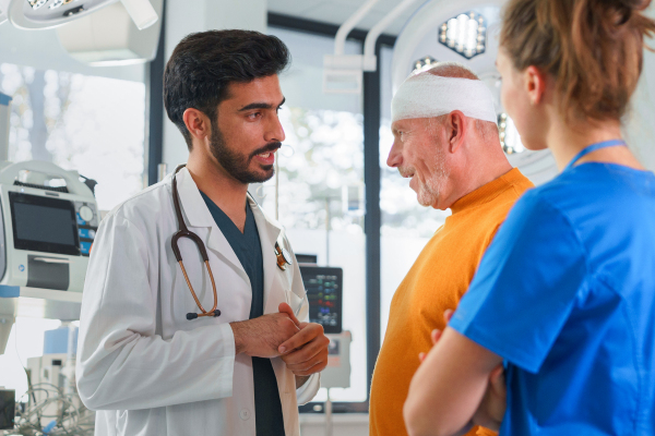 Young doctor and nurse consulting health condition with injured senior man.