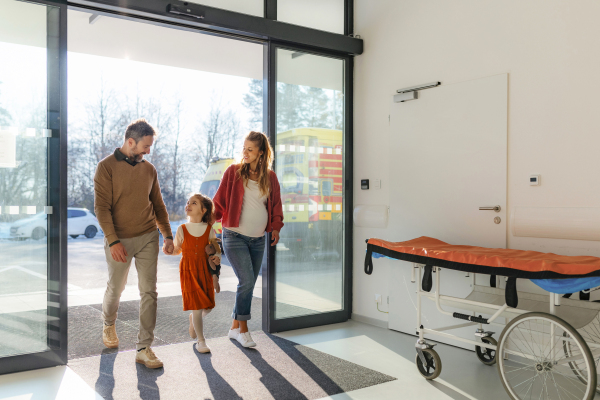 Girl patient arriving at modern clinic for and examination with her parents. Emotional support during medical examination in hospital.