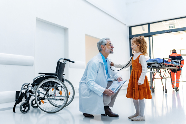 Little girl listening to the doctor's heart with stethoscope. Role reversal. Friendly relationship between the doctor and the child patient.