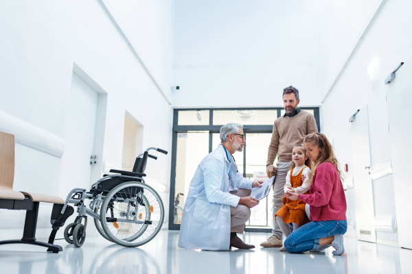 Pediatrician talking with girl's parents. Girl patient is at examination in a modern clinic with her parents. Emotional support during medical examination in hospital.