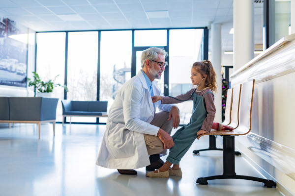 Little girl listening to the doctor's heart beat with stethoscope. Role reversal. Friendly relationship between the doctor and the child patient.