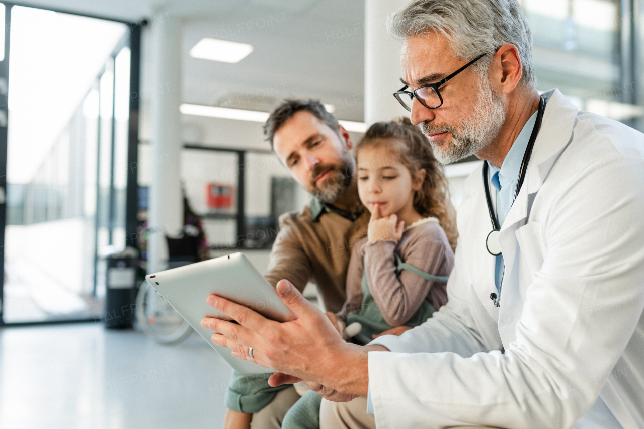 Doctor explaining results of MRI scan of brain to father of young girl patient. Diagnosis of diseases and head injuries. Concept of children healthcare and emotional support for child patients.