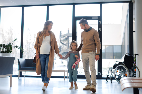 Girl patient looking forward to her doctor and examination in a modern clinic. Girl arriving in hospital with her parents. Emotional support during medical examination in hospital.