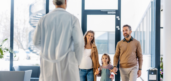 Girl patient looking forward to her doctor and examination in a modern clinic. Girl arriving in hospital with her parents. Emotional support during medical examination in hospital.