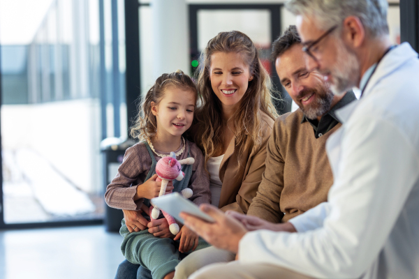 Doctor explaining results of MRI scan of brain to parents of young girl patient, delivering good news. Diagnosis of diseases and head injuries. Concept of children healthcare and emotional support for child patients.