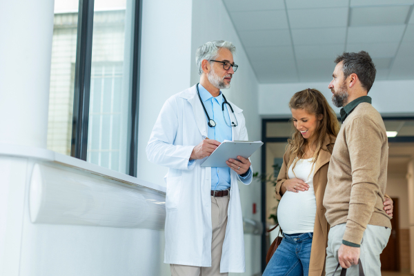 Pregnant woman and husband talking to obstetrician in hospital. Admitting woman in labor to maternity ward, planned cesarean section.