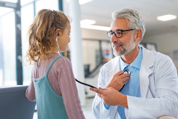 Little girl listening to the doctor's heart beat with stethoscope. Role reversal. Friendly relationship between the doctor and the child patient.