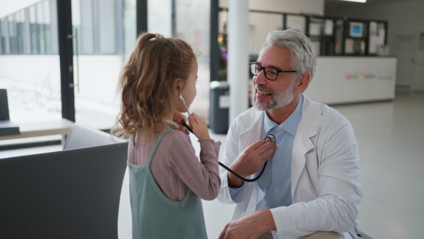 Close up of doctor examining little girl's ear using otoscope, looking for infection. Friendly relationship between the doctor and the child patient.