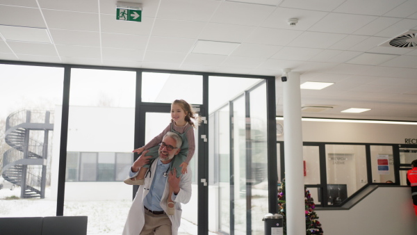 Video of a pediatrician with a little patient sitting on his shoulders, piggyback. Doctor carrying girl on shoulders. Friendly relationship between the doctor and the child patient.