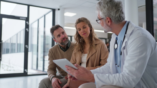 Doctor explaining results of MRI scan of brain to mature couple, delivering good news. Diagnosis of diseases and head injuries.