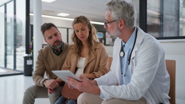 Doctor explaining results of MRI scan of brain to mature couple, delivering good news. Diagnosis of diseases and head injuries.