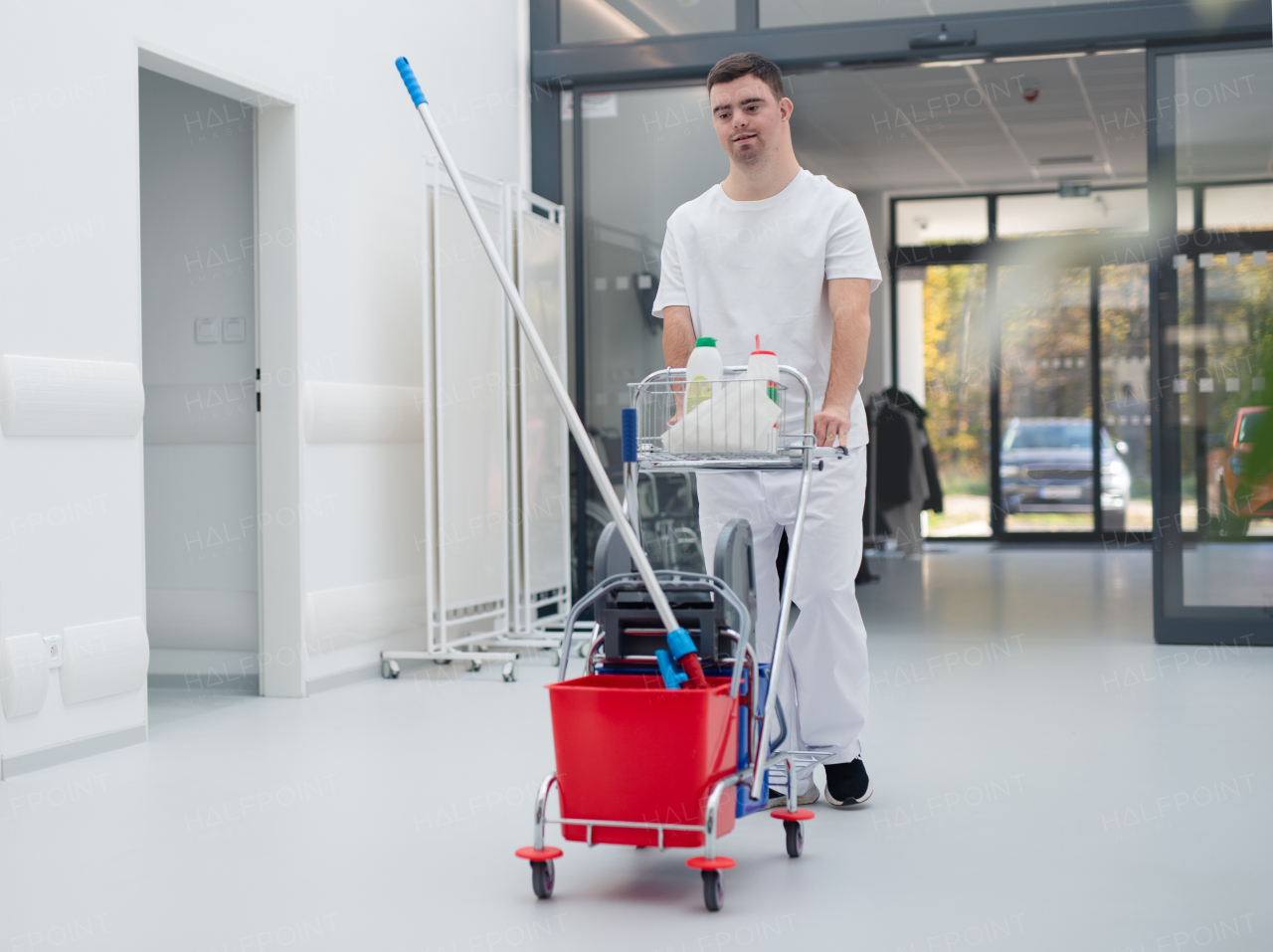 Young man with down syndrome working in hospital as cleaner. Concpet of integration people with disability into society.